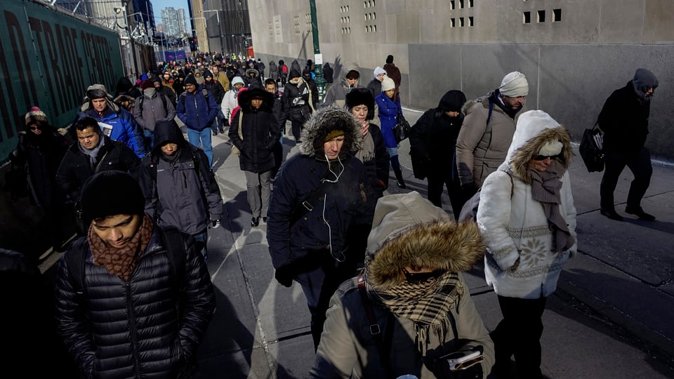 Menschen in Lower Manhattan in dicke Jacken gepackt.
