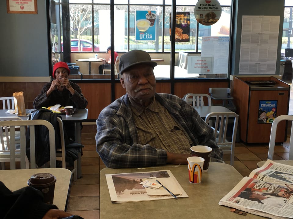 Ein alter Mann an einem Tisch in einem Mc Donald's.