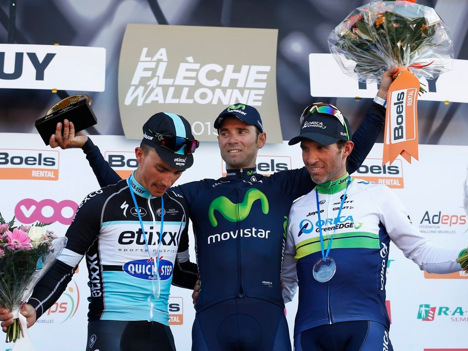 Alejandro Valverde jubelt mit Blumenstrauss und Pokal in den Händen, neben ihm stehen Julien Alaphilippe und der Schweizer Michael Albasini.