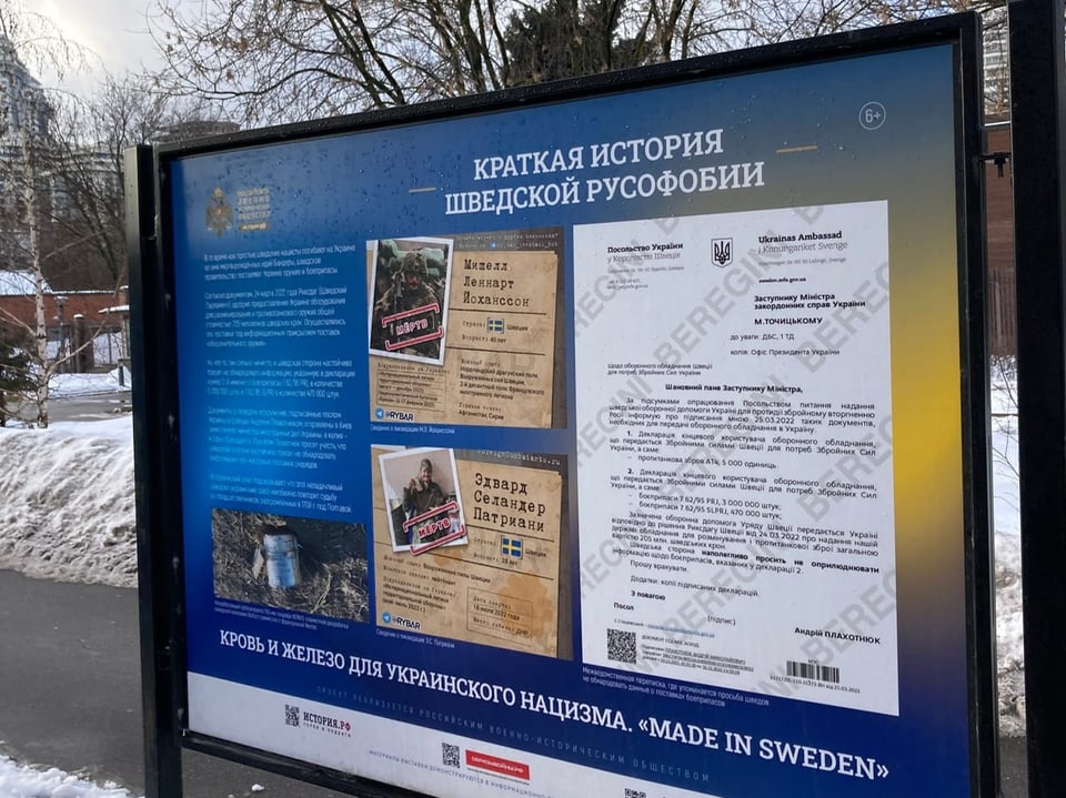 blaue Tafel mit alten Fotos darauf und weisser Schrift, auf russisch.