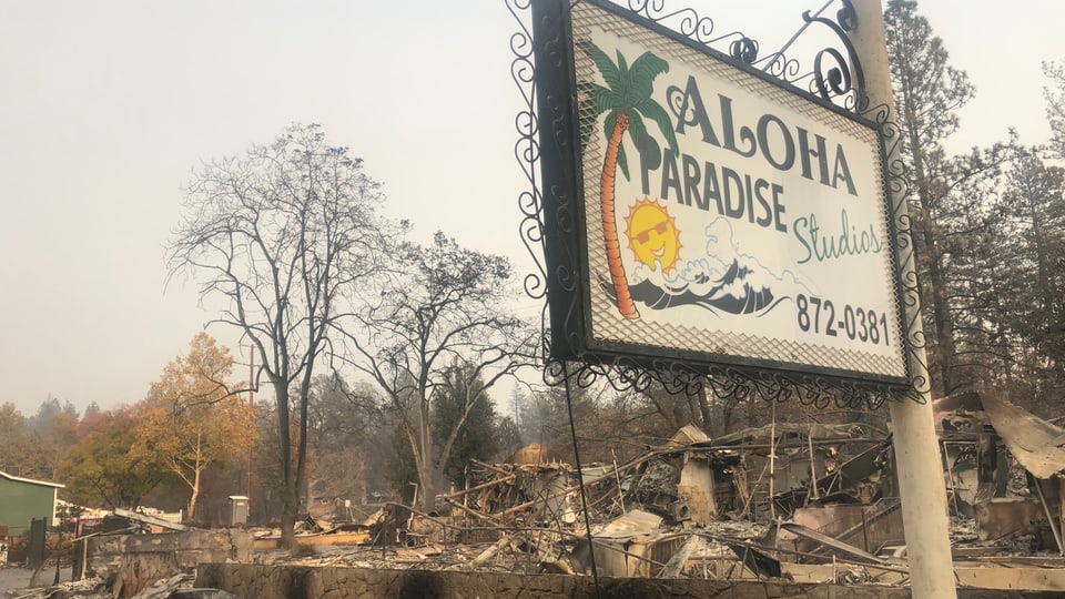 Ein Schild f¨ür «Aloha Paradise» in mitten von Überresten des Feuers