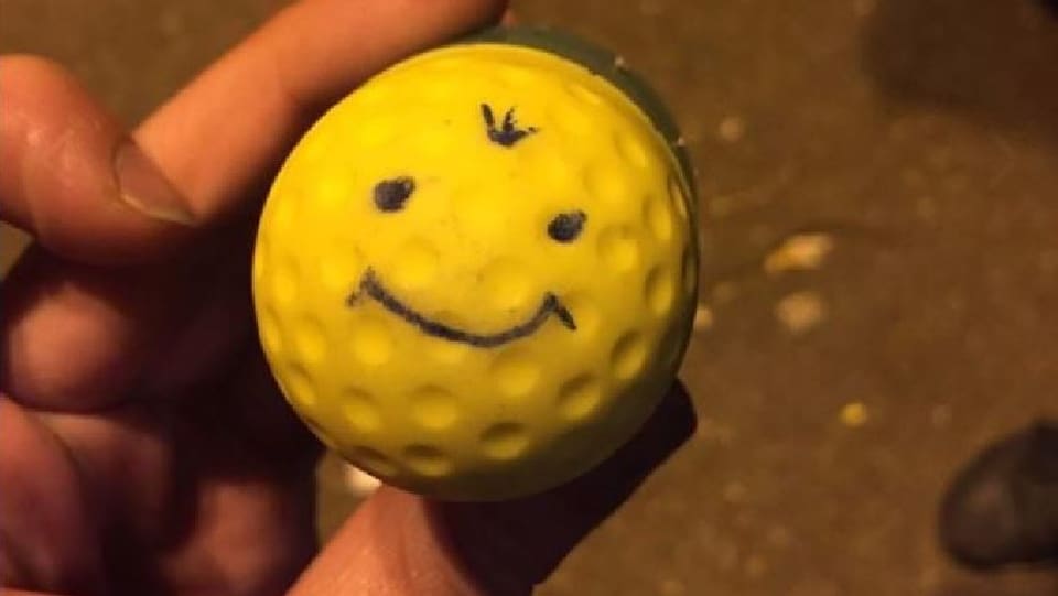 Gelbes rundes Gummigeschoss mit aufgezeichnetem lächelndem Gesicht