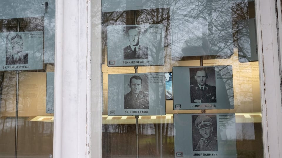 Durch ein Fenster sieht man eine Ausstellung über den Nationalsozialismus. Fotos von Vertretern der SS sind ausgestellt.
