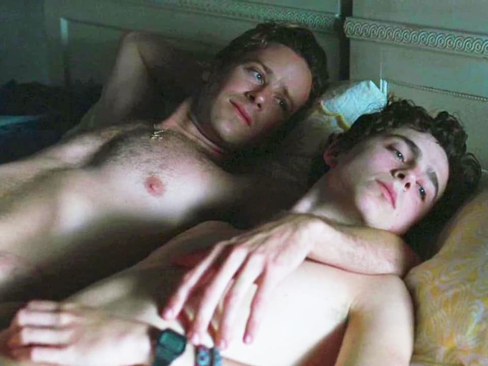 Zwei junge Männer liegen entspannt nebeneinander im Bett.