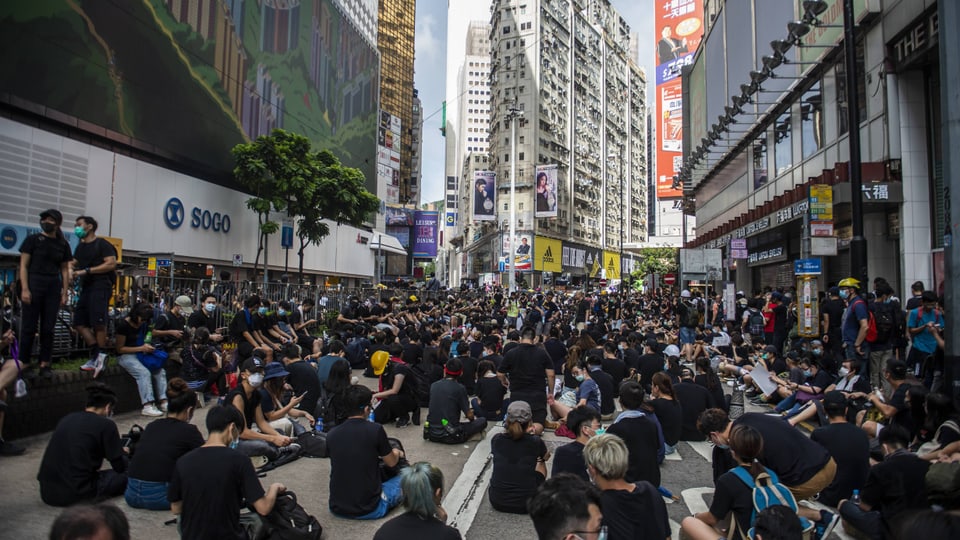 Menschen sitzen auf einer Strasse in Hongkong.