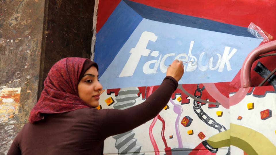 Eine Studentin in Kairo malt den Facebook-Schriftzug an eine Wand - als ein Zeichen für die Revolution.  