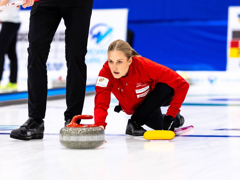 Spielerin beim Curling gleitet auf dem Eis und stösst einen Stein.