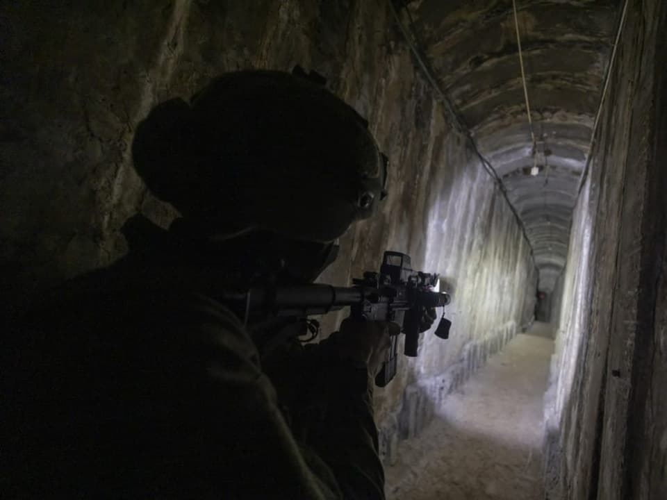 Person in Militärausrüstung zielt mit Gewehr in einem dunklen Tunnel.
