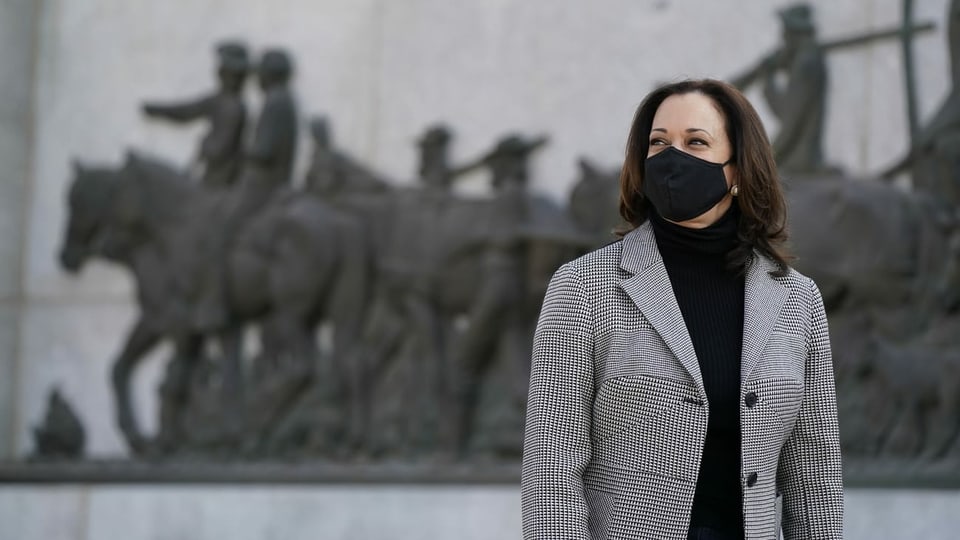 Harris mit Maske vor einem Denkmal.