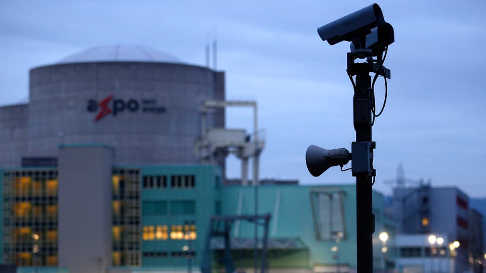 Aufnahme des AKW Beznaus. Im Bildvordergrund ist ein Mast zu sehen, an den eine Videokamera und ein Lautsprecher montiert sind.