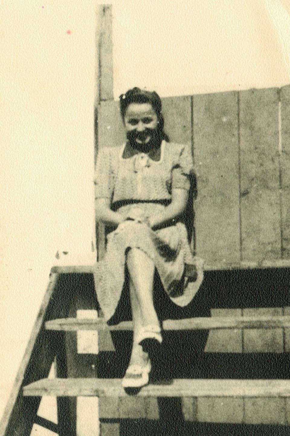 Eine junge Frau auf einem Schwarzweissbild sitzt auf einer Treppe.