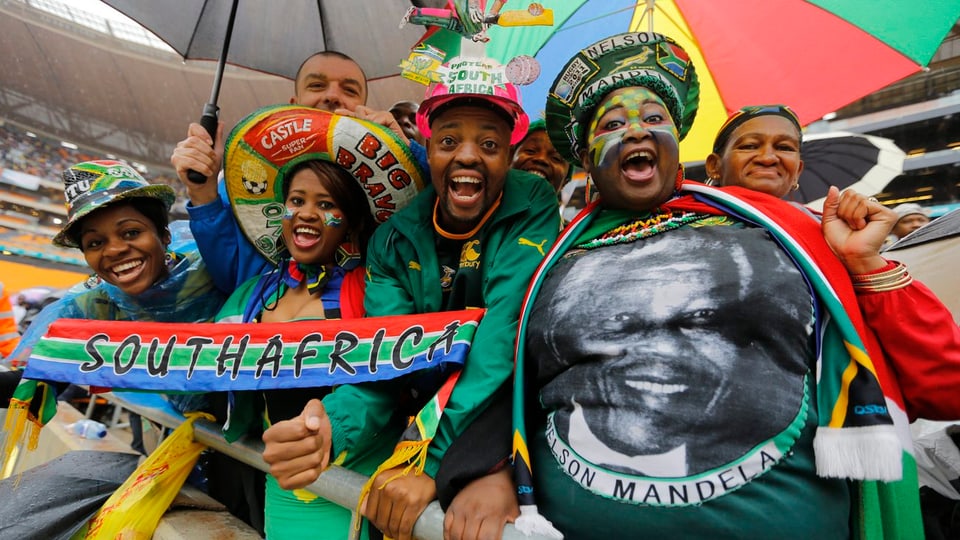Mehrere Afrikaner, die T-Shirts mit dem Aufdruck von Mandela und Fahnen auf sich tragen