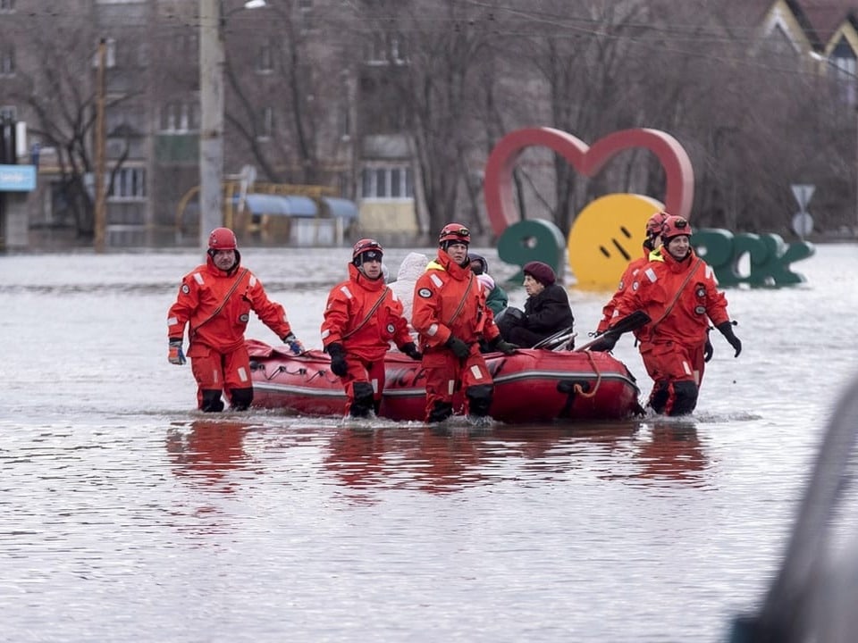 Helfer ziehen ein Rettungsboot mit betroffenen Menschen in Orsk.