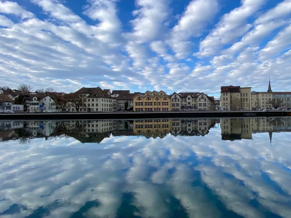 Schaffhausen/SH Blick über einen Fluss auf Stadt. Der Himmel blau mit weissen Streifen, die sich im Wasser spiegeln.
