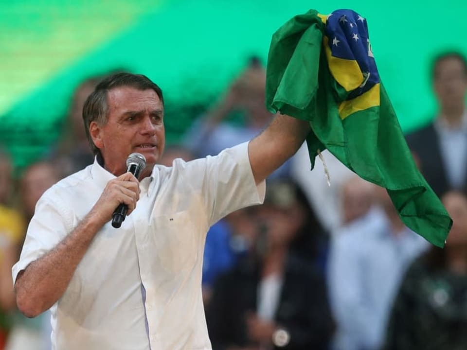 Jair Bolsonaro streckt eine Brasilienflagge in die Höhe.