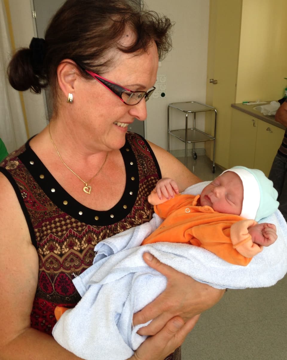 Im Spitalzimmer hält Frau Hiestand das in eine Decke gehüllte Neugeborene auf dem Arm.