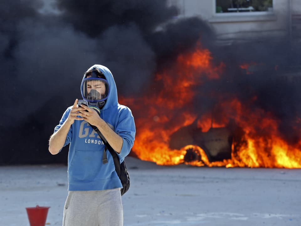 Ein Demonstrant guckt auf sein Handy.