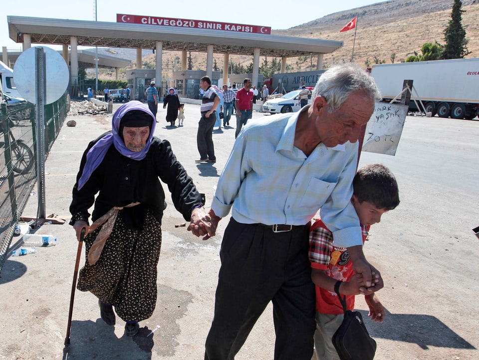 Zwei ältere Personen und ein Junge passieren die türkische Grenze