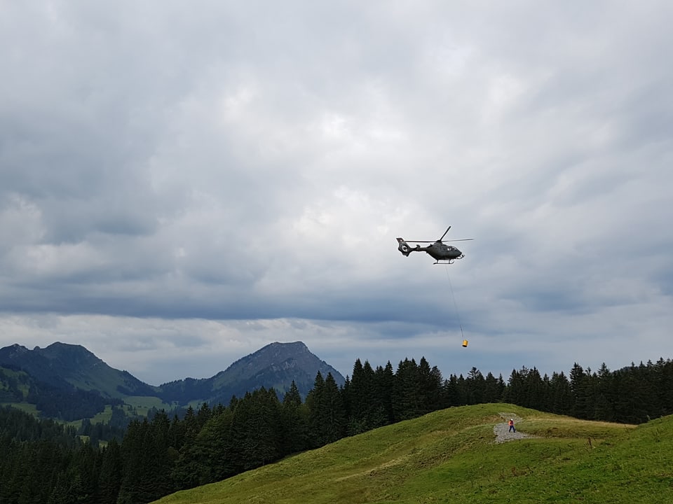 Helikopter in der Luft mit Abfalltonne dran