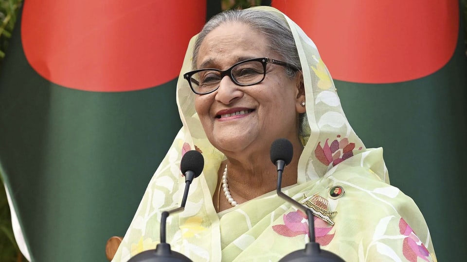 Sheikh Hasina hält eine Rede und spricht in Mikrofone.