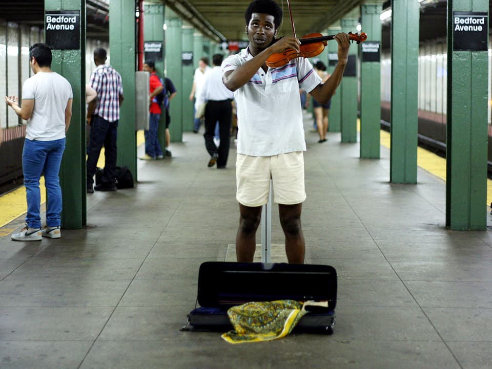 Mann spielt Geige auf dem Perron.
