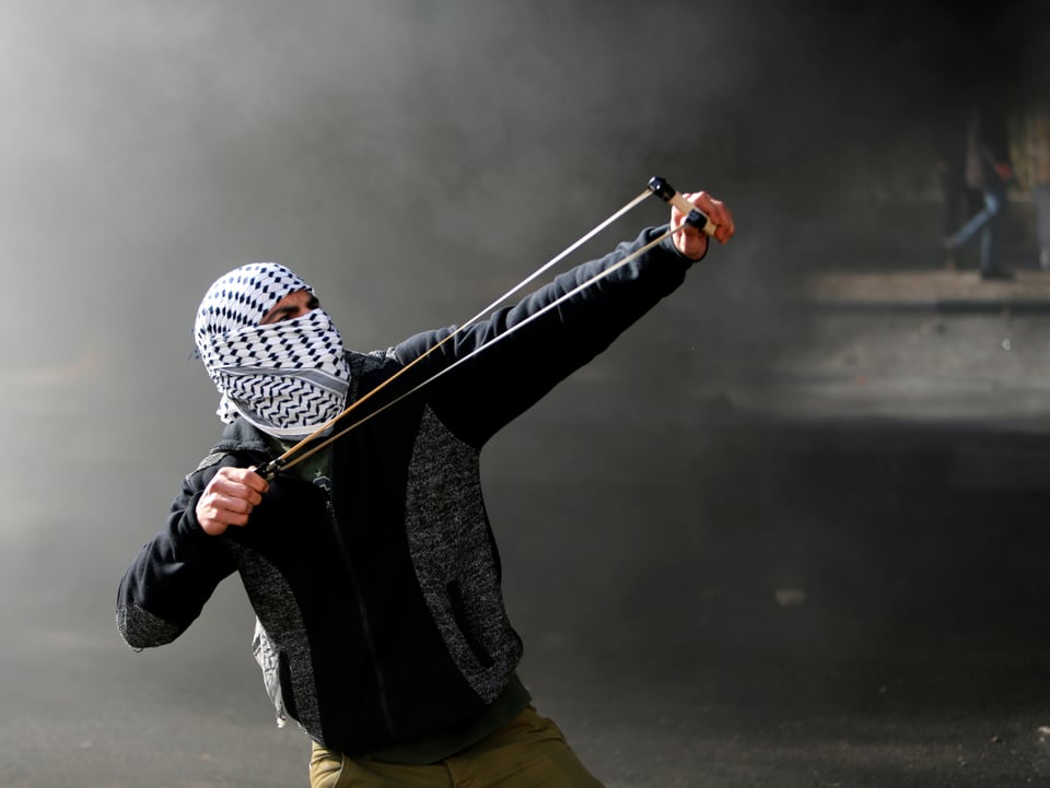 Ein palästinensischer Demonstrant schleudert Steine ​​auf israelische Truppen.