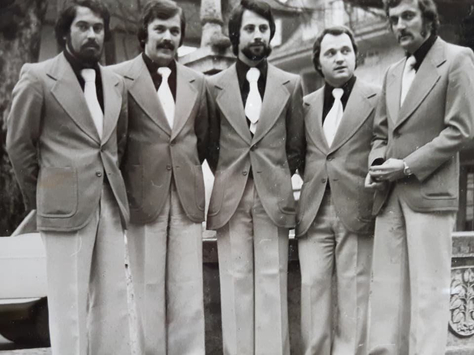 Band trägt Anzüge im Look der 1970er Jahre.