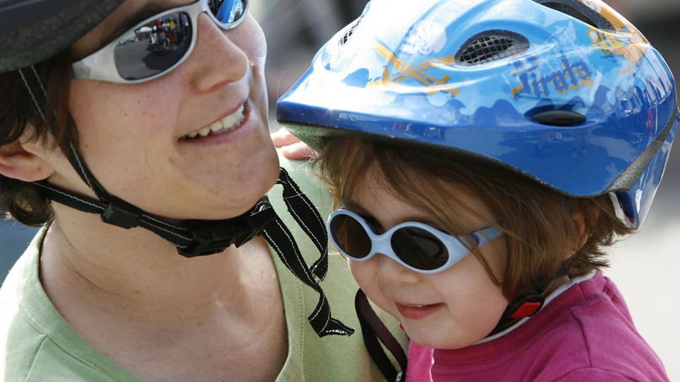 Kleines Mädchen mit Sonnenbrille und Velohelm.