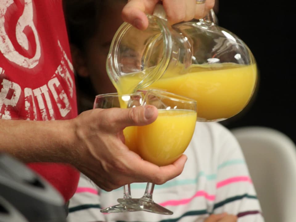 Orangensaft wird in Gläser gegossen.