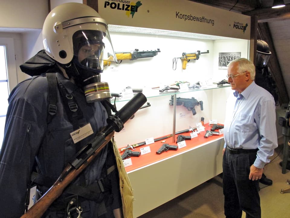 Ex-Polizist Rolf Tuchschmid  vor der Vitrine der Polizebewaffnung.