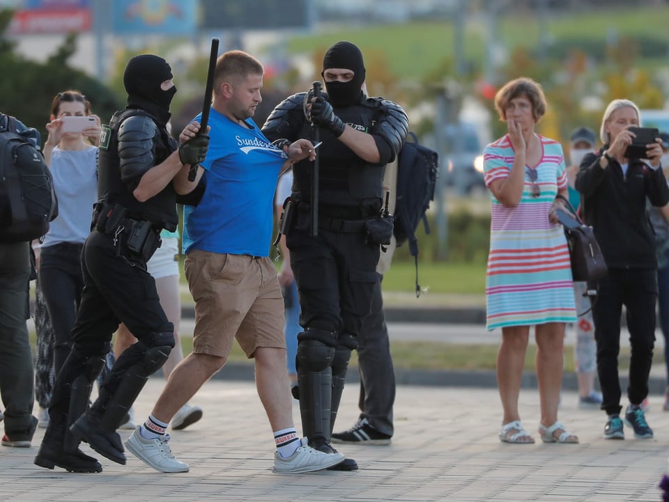 Ein Mann wird von zwei uniformierten Polizisten abgeführt.