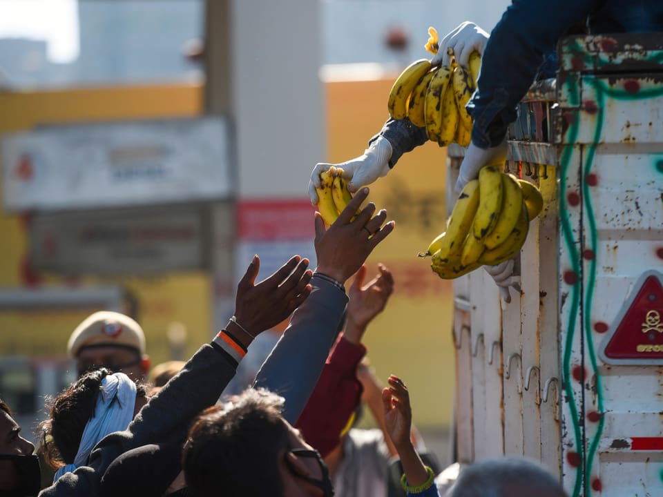 Person verteilt Bananen an Wanderarbeiter
