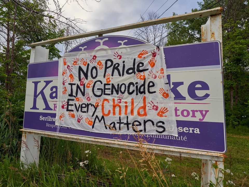 Ein Plakat klebt auf einer Schulanzeige mit der Aufschrift «No Pride in Genocide, every Child matters».