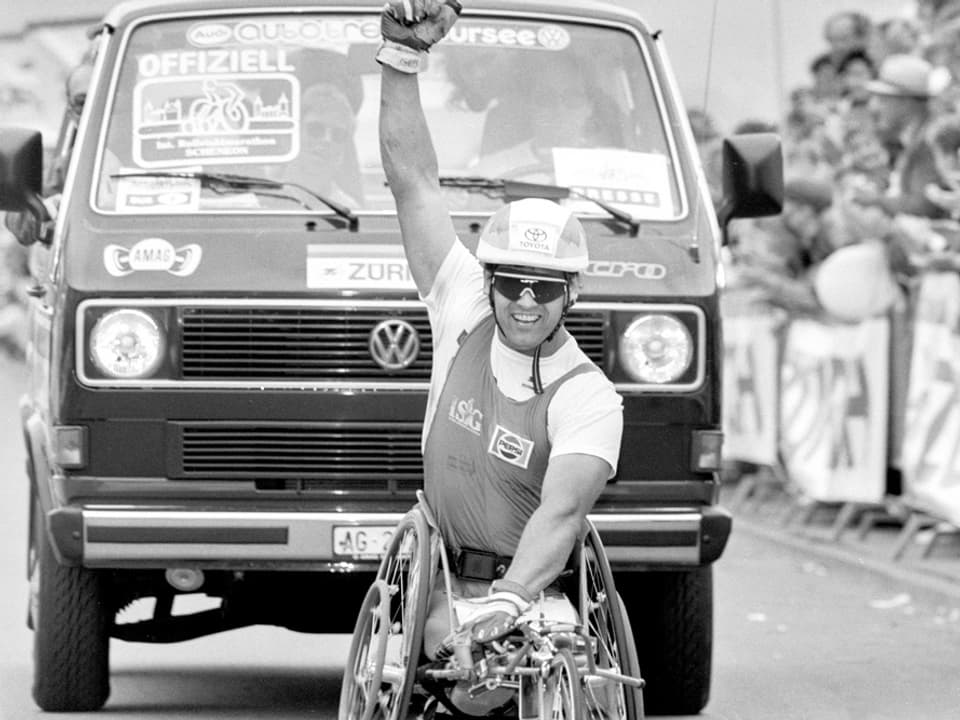 Schwarz-weiss-Foto eines Rollstuhlsportlers vor einem alten VW-Bus