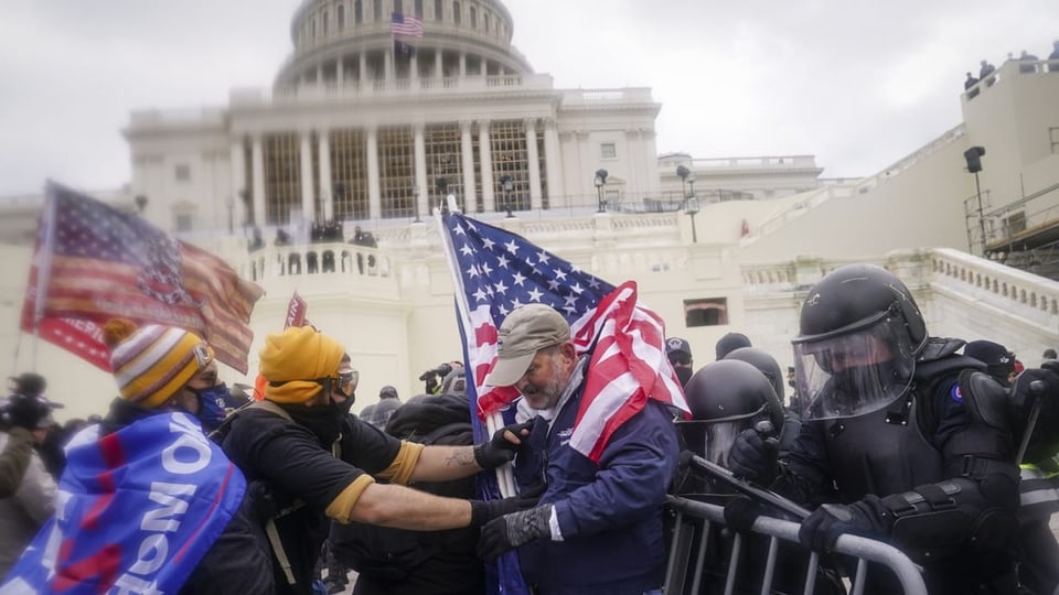 Menschen stürmen das US-Kapitol und tragen Fahnen mit sich