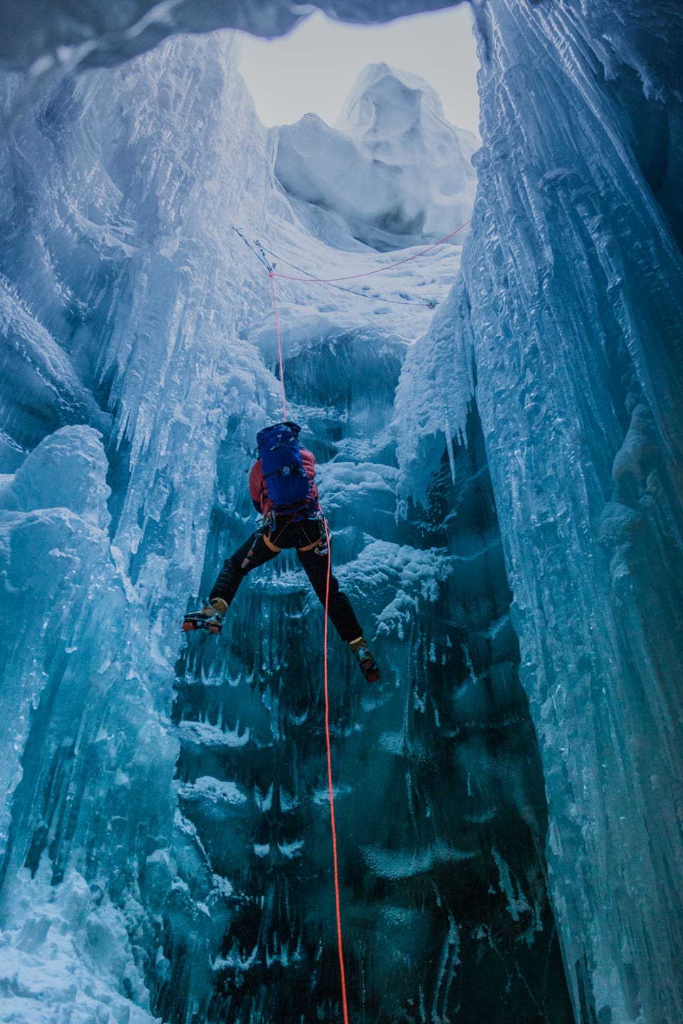 Ein Mann steigt an einem Seil den Gletscher hinab.