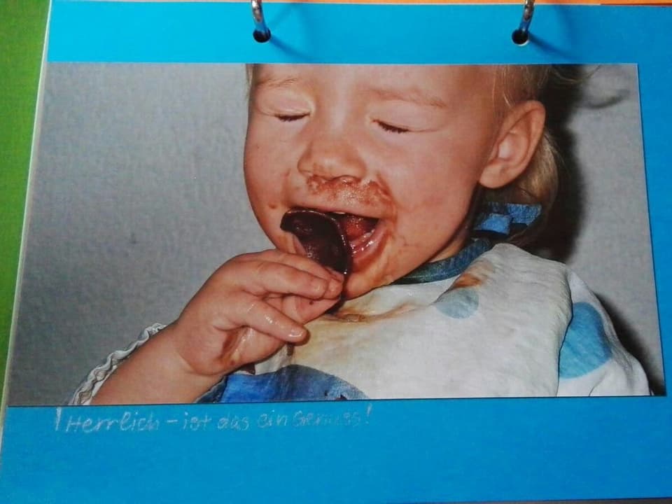 Ein Kleinkind auf einem Foto im Fotoalbum isst Schololade.