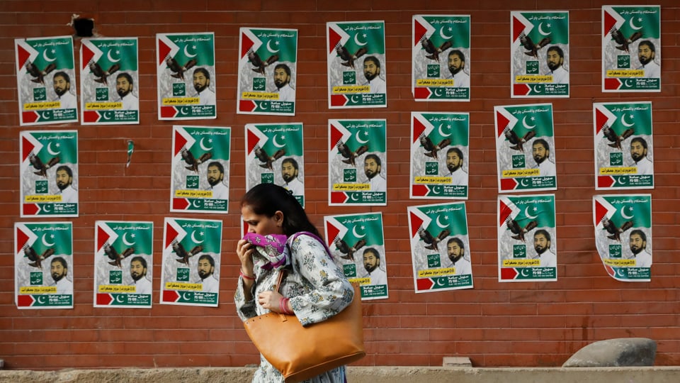 Frau läuft an Wand mit Wahlplakaten vorbei
