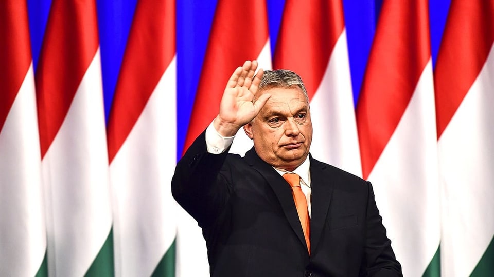 Ungarns Regierungschef vor dem Meer ungarischer Flaggen, den rechten Arm zum Gruss erhoben.