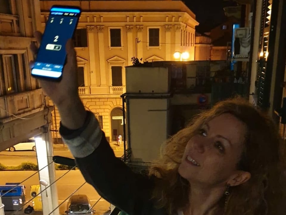 Frau in Italien hält Handy aus dem Fenster, um Lichtstrahlung zu messen.