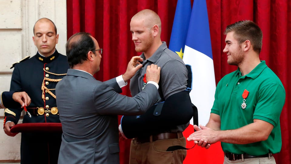 Hollande steckt Spencer Stone die Medaille ans T-Shirt. Neben ihm steht Alek Skarlatos, der schon eine Medaille trägt