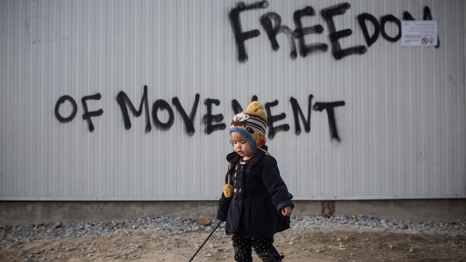 Ein Kleinkind vor einer Wand mit der Aufschrift «Freedom of movement»