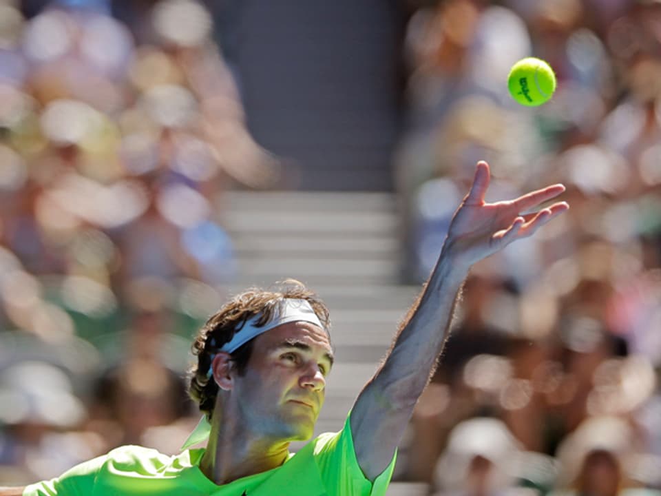 Roger Federer wirft für den Anschlag einen Tennisball in die Luft.