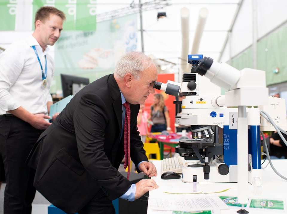 Bundesrat Johann Schneider-Ammann schaut in ein Mikroskop.