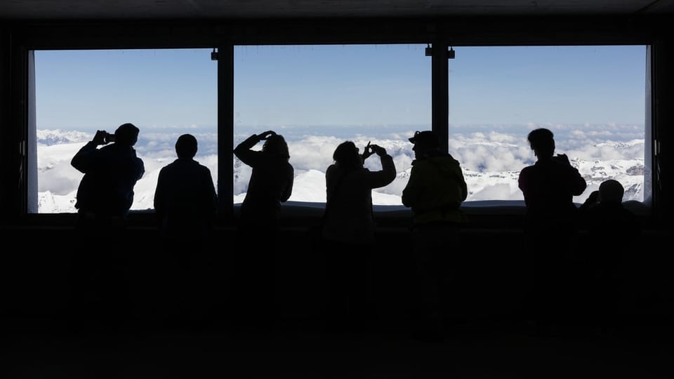 Menschen stehen vor einem Fenster auf dem Jungfraujoch. 