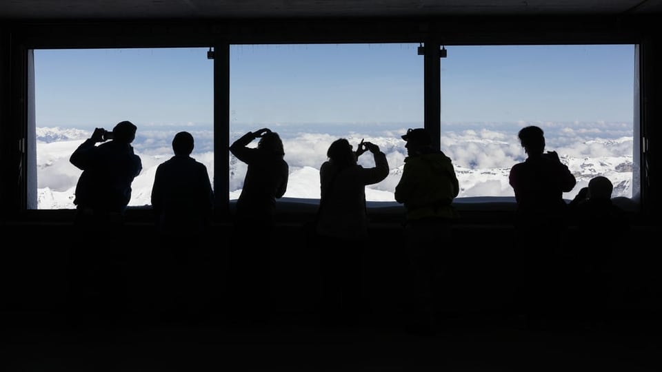 Menschen stehen vor einem Fenster auf dem Jungfraujoch.