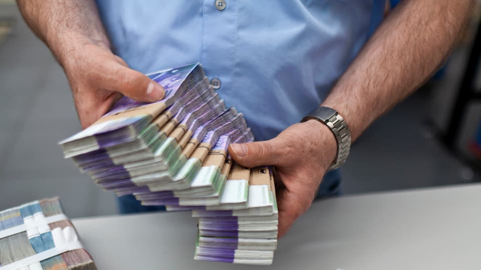 Ein Mann hält ein Bündel 1000er-Noten.