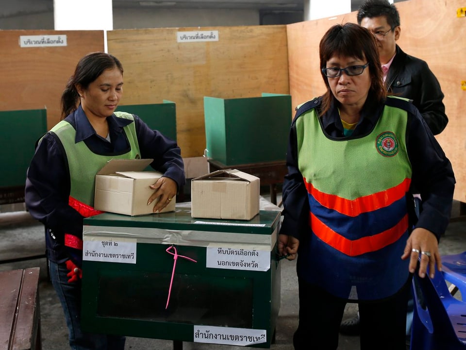 Zwei Frauen transportieren in Thailand eine Wahlurne