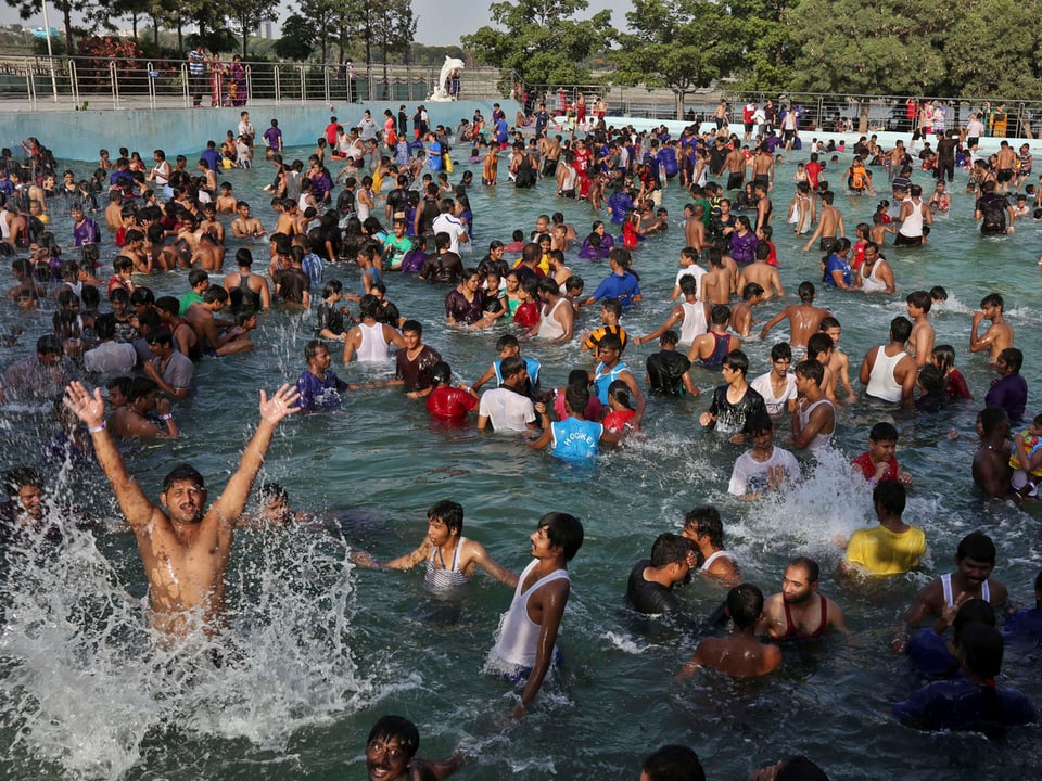 Eine Vielzahl an Menschen badet im Wasser