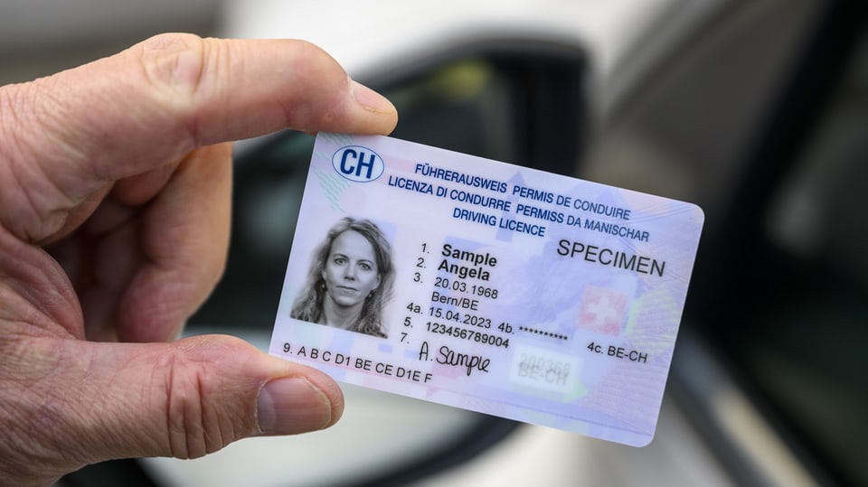 Hand hält einen Führerausweis im Kreditkartenformat, darauf eine Frau mit dem fiktiven Namen Angela Sample